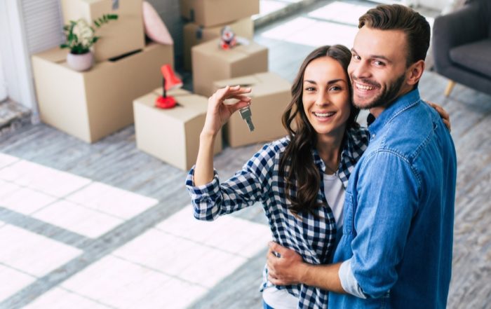 A young couple holds happily a key to their new home which they were so excited about, and this can't but make them feel overwhelmed with positive emotions.